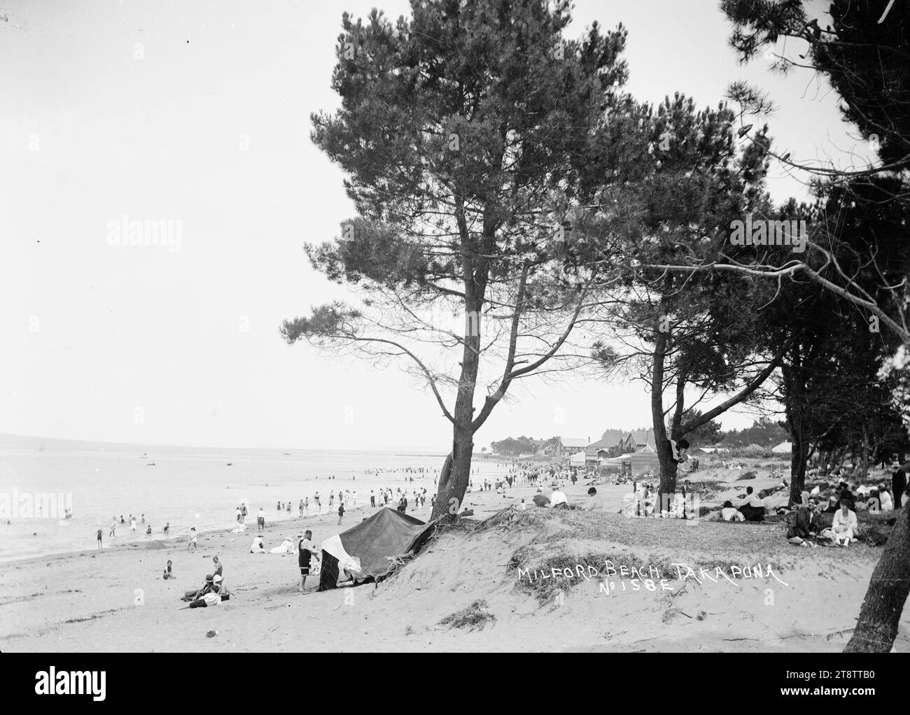 Milford Beach, Auckland, nuova Zelanda, Vista di Milford Beach presa da un'area vicino agli alberi dietro la spiaggia che guarda a sud-est. La gente può essere vista nuotare e camminare sulla spiaggia. ca 1914 Foto Stock