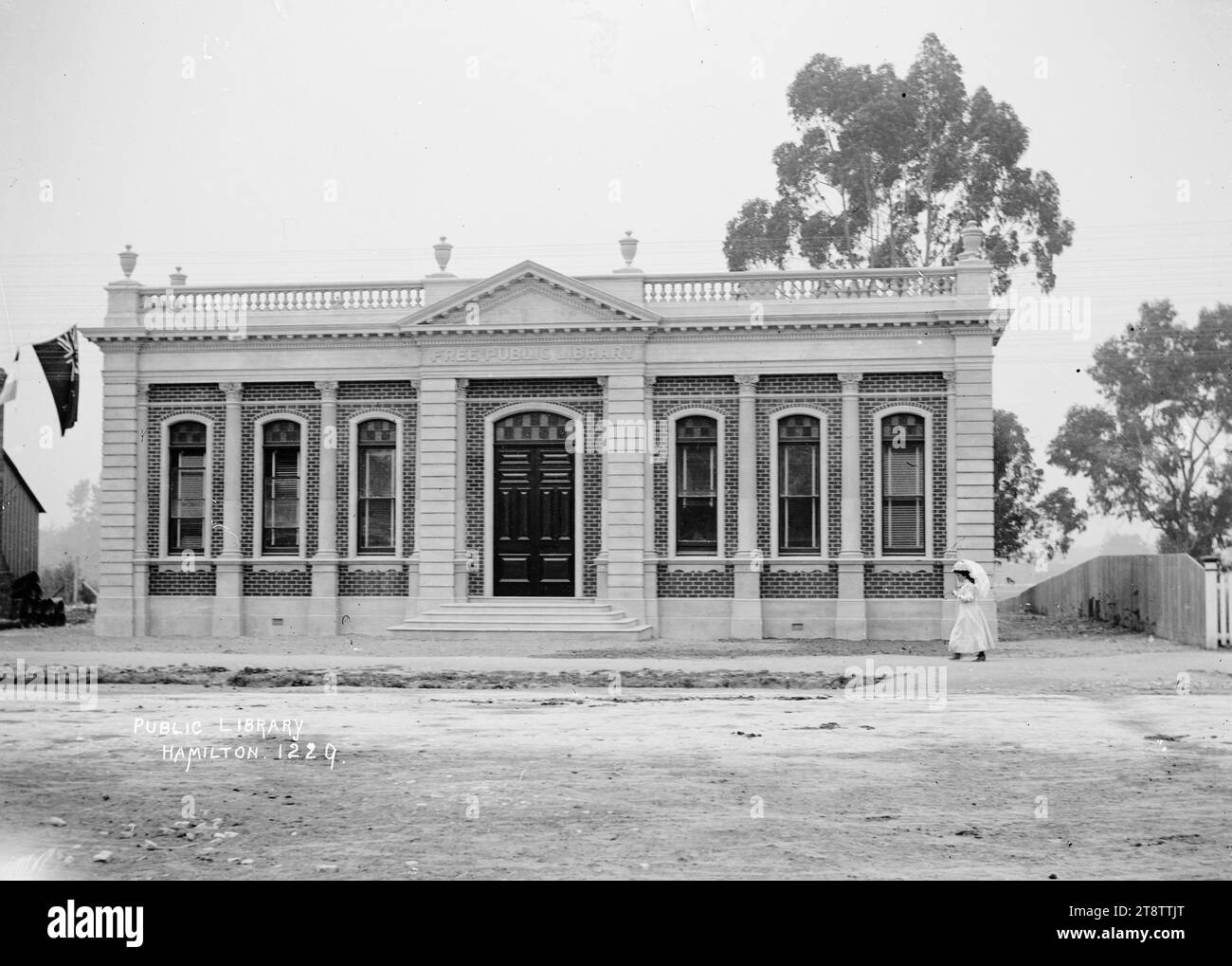 Hamilton Public Library, la Hamilton Public Library il giorno dell'apertura ufficiale di Sir Joseph Ward. Scattato il 17 febbraio 1908, . Le bandiere cerimoniali sono appese a sinistra dell'edificio, e c'è una giovane donna con un ombrellone che passa davanti alla biblioteca Foto Stock
