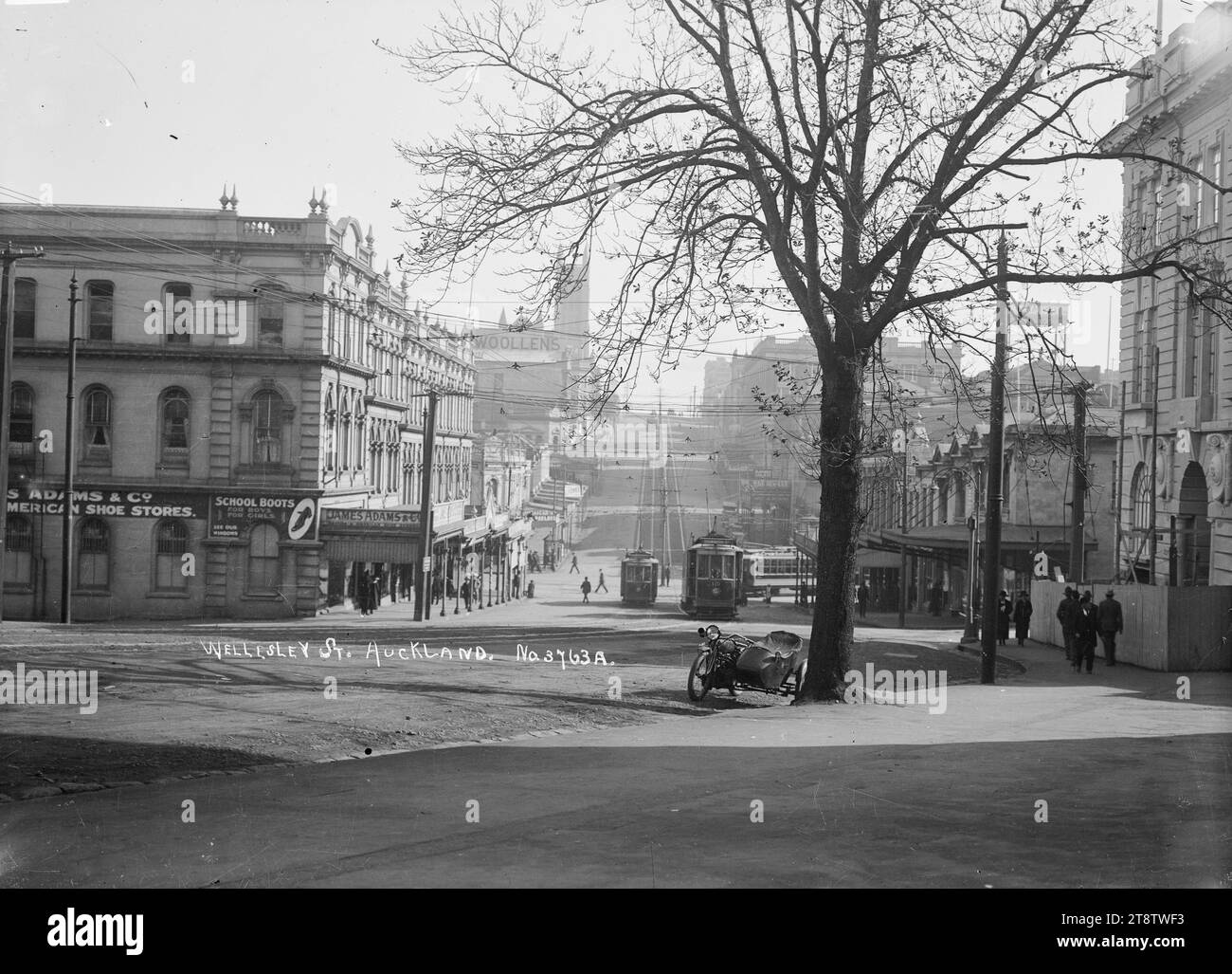 Wellesley Street, Auckland, nuova Zelanda, Vista di Wellesley Street, Auckland, nuova Zelanda, dall'esterno di Auckland, New Zealand Public Library. I tram corrono in entrambe le direzioni lungo la strada e James Adams & Co, i negozi di scarpe americani, possono essere visti a sinistra dell'immagine. L'incrocio tra Wellesley e Queen Street può essere visto al centro dell'immagine. Una motocicletta con side-car è parcheggiata sotto un albero in primo piano. Fotografato intorno al 1910 Foto Stock