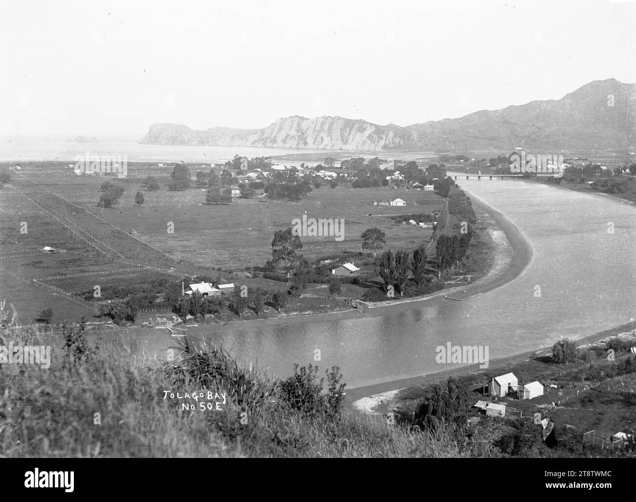 Fiume Uawa, Baia di Tolaga, vista a sud-est della Baia di Tolaga con il fiume Uawa in primo piano e a destra. La cittadina e il ponte possono essere visti a media distanza, mentre la costa e le Mitre Rocks a distanza molto lontana. Fotografia scattata nel 1900-1930 circa Foto Stock