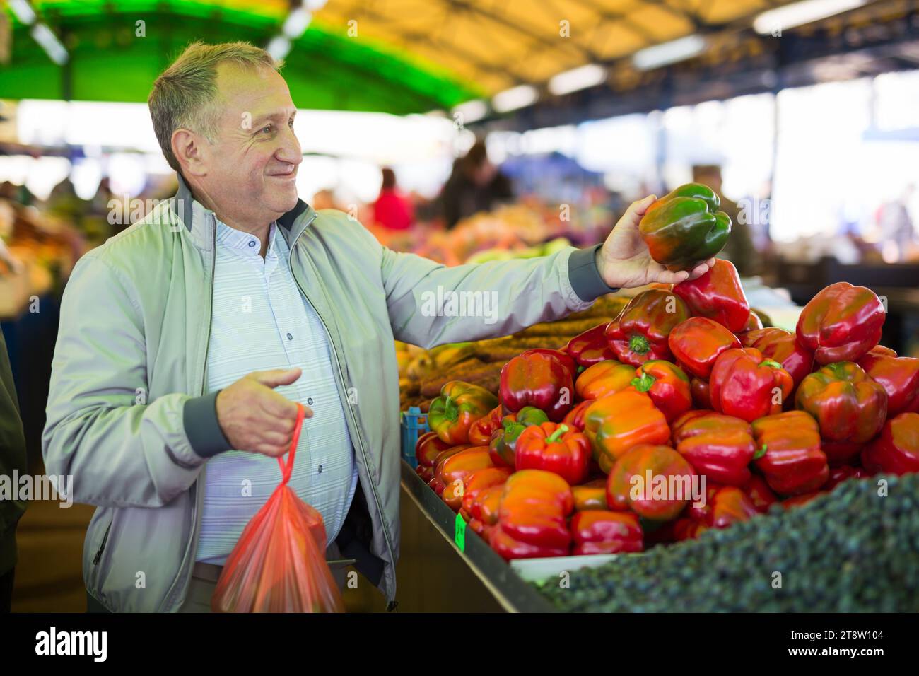 Uomo che acquista peperoni in gregrocery Foto Stock