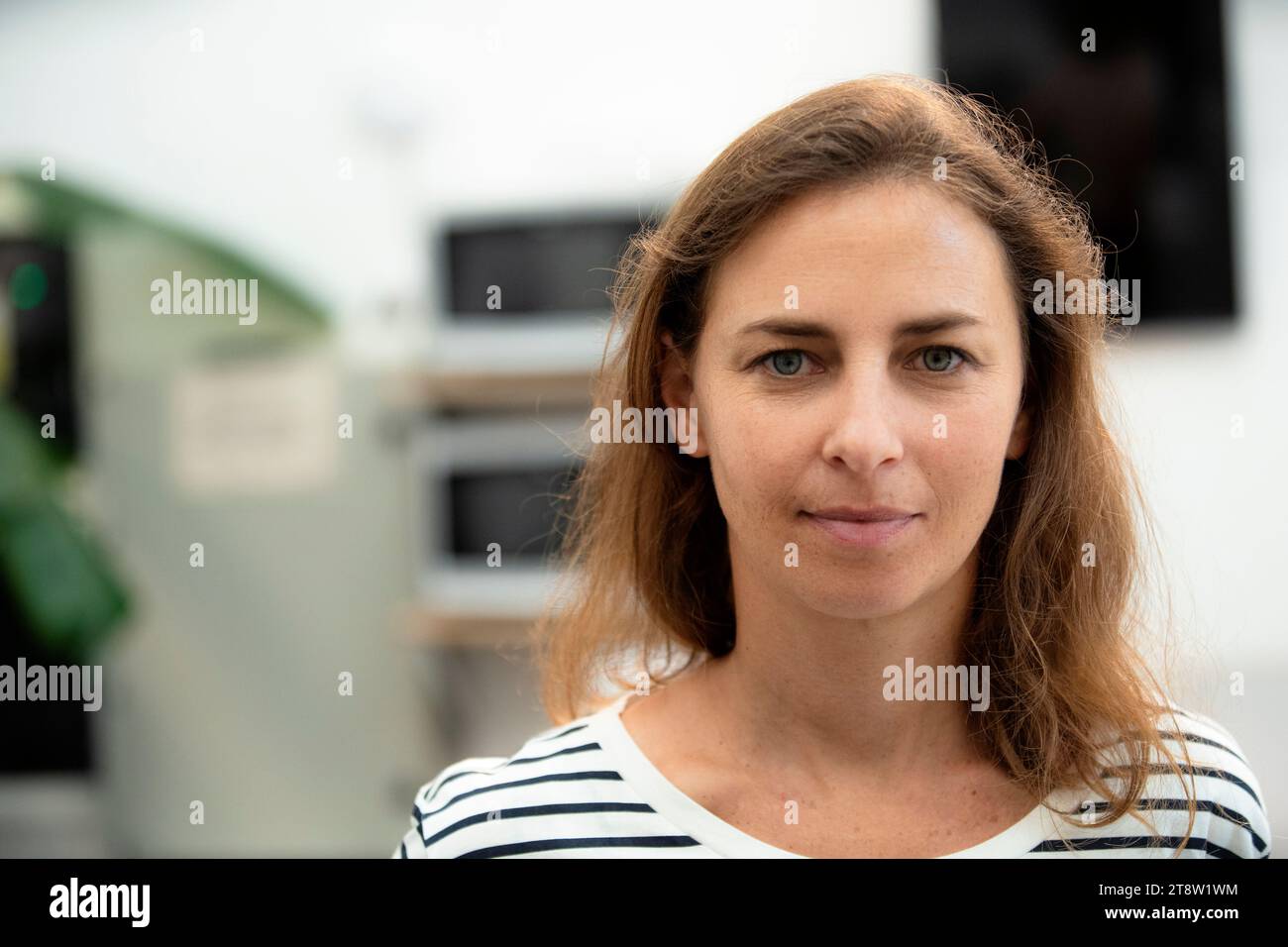 Donna adulta che guarda la telecamera mentre si trova in posizione interna Foto Stock