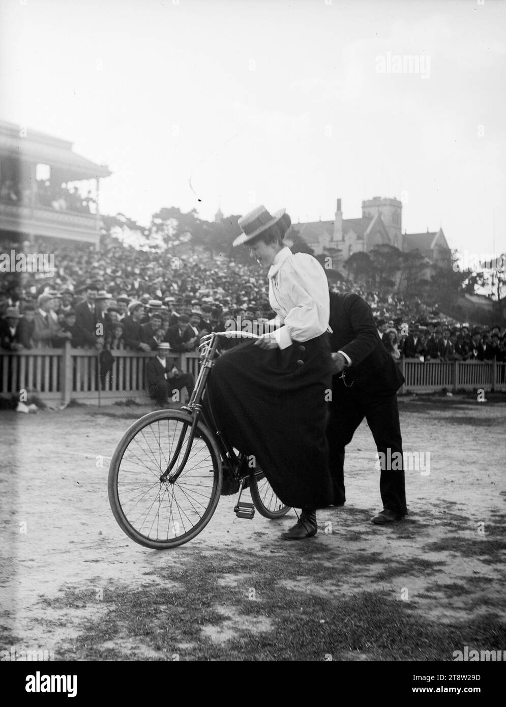 Concorrente femminile in una gara ciclistica, assistita da un titolare, CA 1900 Foto Stock