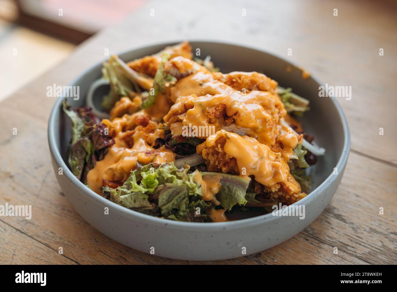 Pollo fritto croccante con insalata mista di lattuga e salsa maionese in un piatto di ceramica su un tavolo di legno Foto Stock