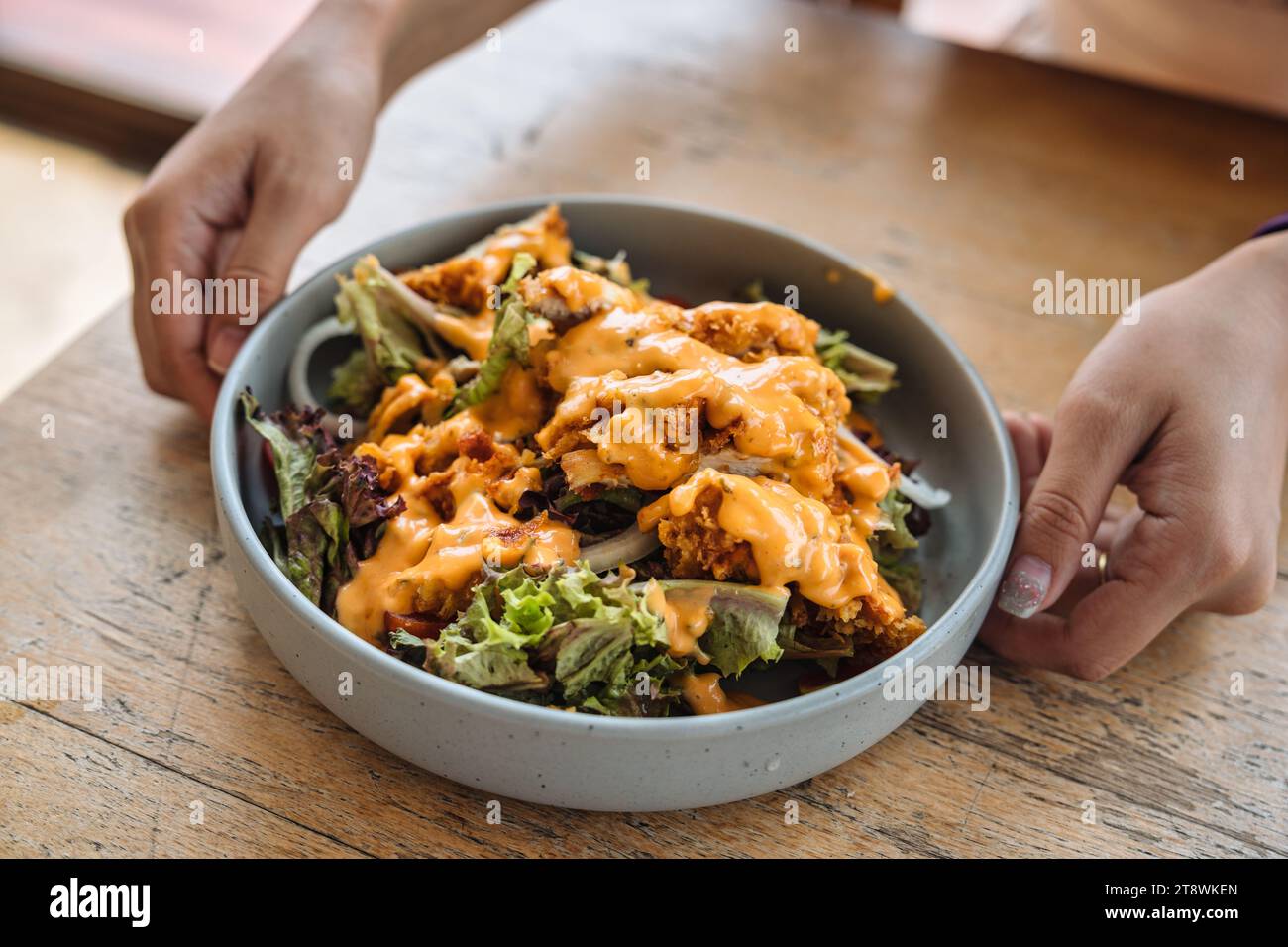 Pollo fritto croccante con insalata mista di lattuga e salsa maionese in un piatto di ceramica su un tavolo di legno Foto Stock