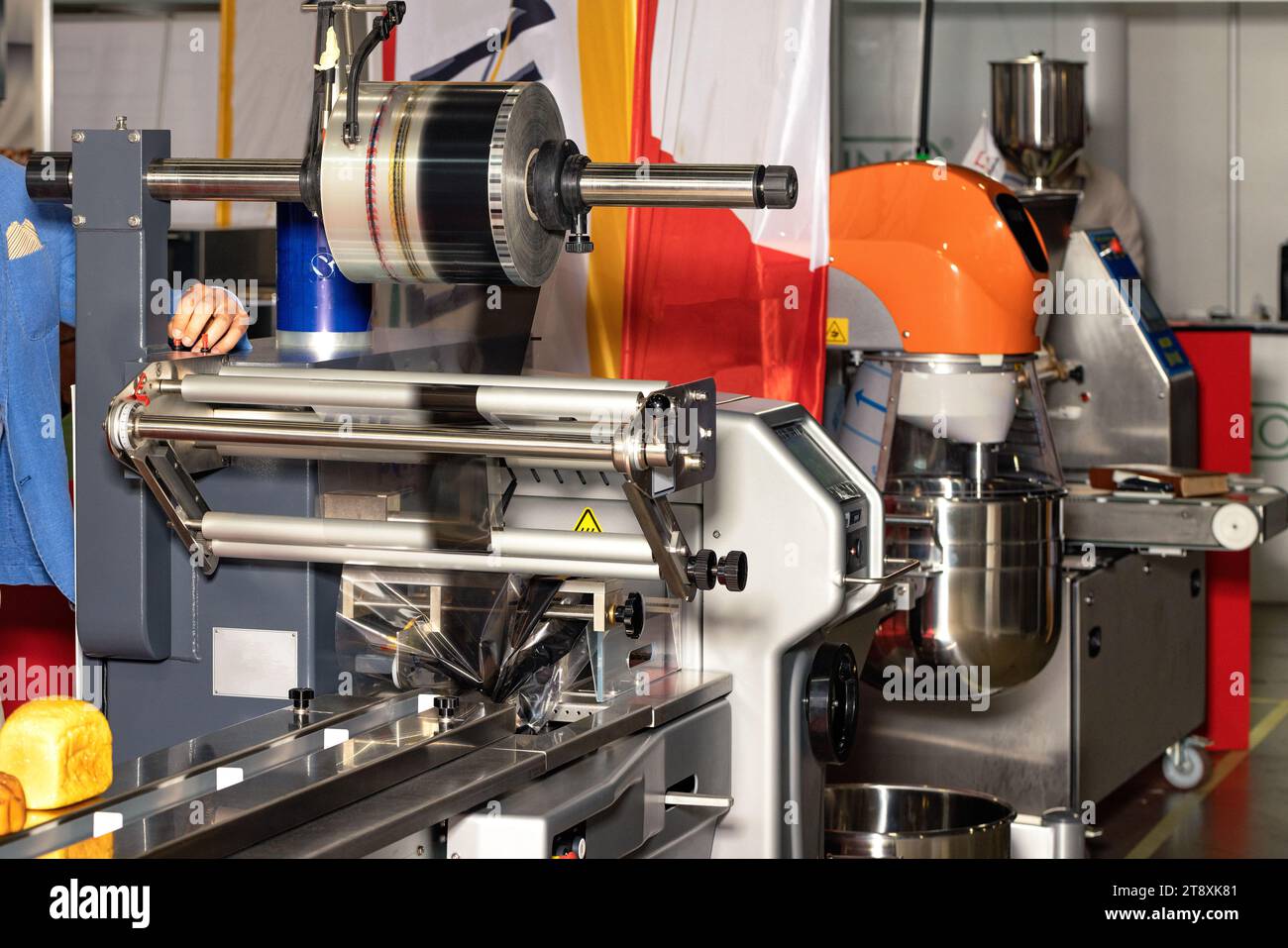 Il pane cotto su un nastro trasportatore si sposta per essere sigillato in una macchina di imballaggio sulla linea di produzione di una fabbrica di prodotti da forno. Foto Stock