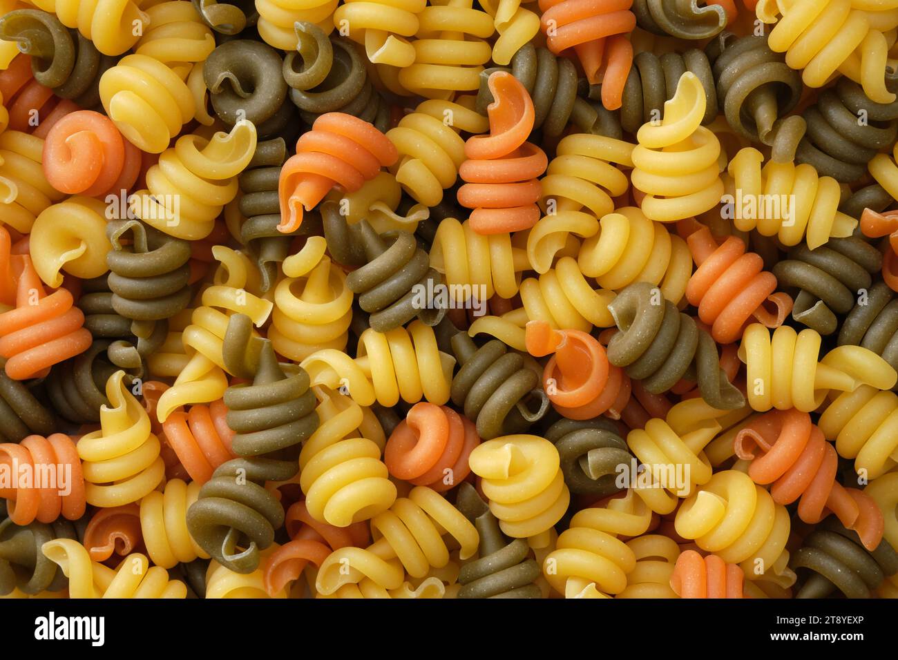 Fondo di pasta a spirale. Pasta di diversi colori, vista dall'alto, piatto. Foto Stock