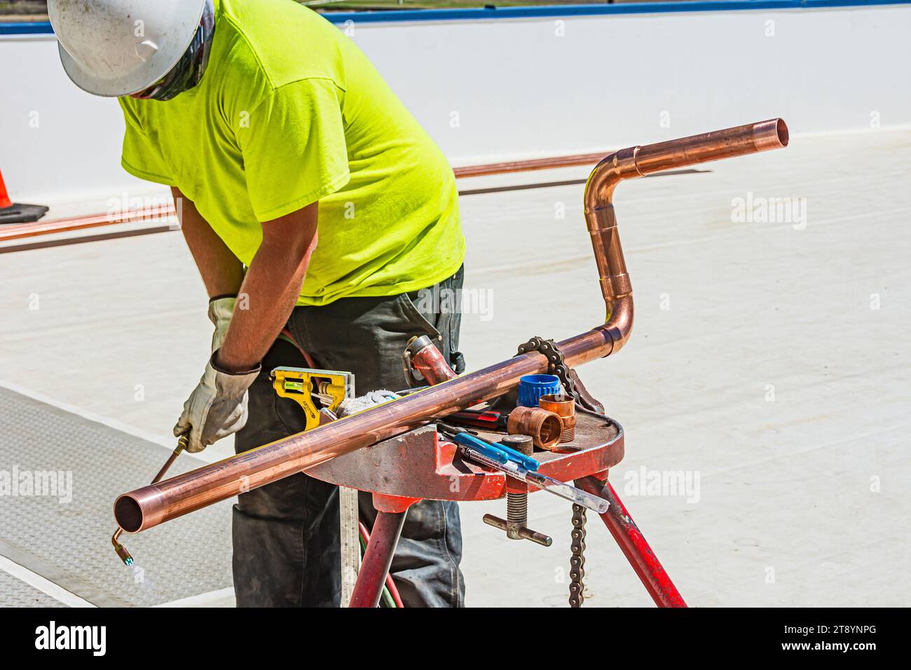 Gomiti di brasatura per operai edili su una lunghezza di tubo di rame sul tetto in un magazzino di stoccaggio a freddo a CO2 (refrigerazione industriale) Foto Stock