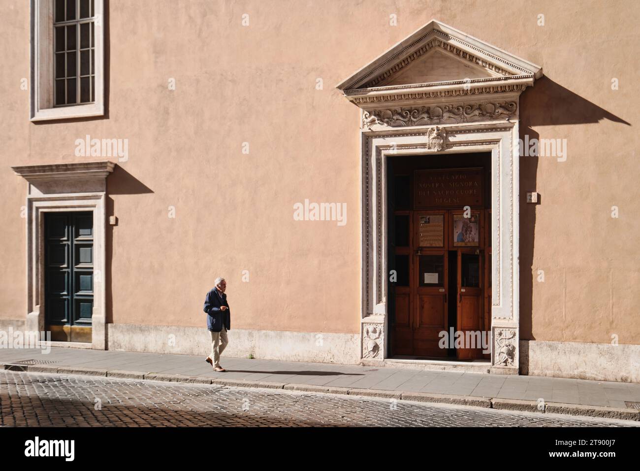 Roma, Italia - ottobre 29 2023: Un vecchio che cammina di fronte a una tipica facciata di architettura romana nel centro città (nostra Signora del Sacro Cu Foto Stock
