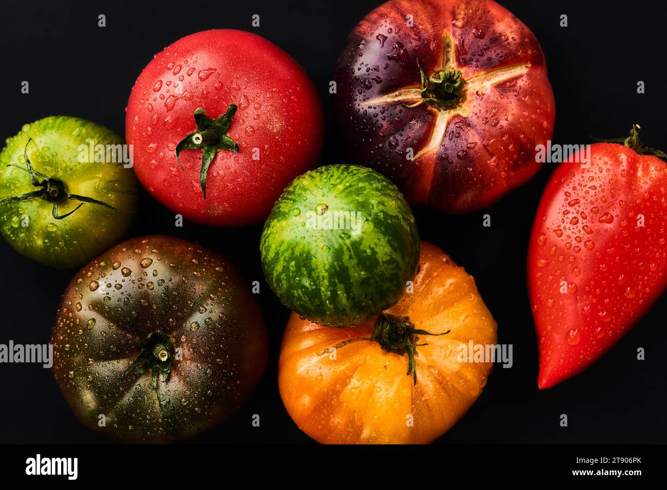 Assortimento di pomodori freschi e umidi con vista dall'alto su sfondo nero Foto Stock