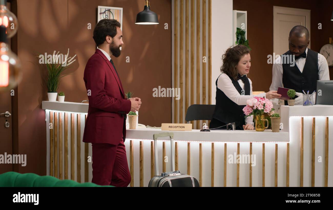 Check-in alla reception dell'hotel. Il dipendente della reception sta esaminando le informazioni sul passaporto per registrare il cliente di un uomo d'affari. Lavoratore di colletti bianchi che arriva al resort dopo un lungo volo d'affari. Foto Stock