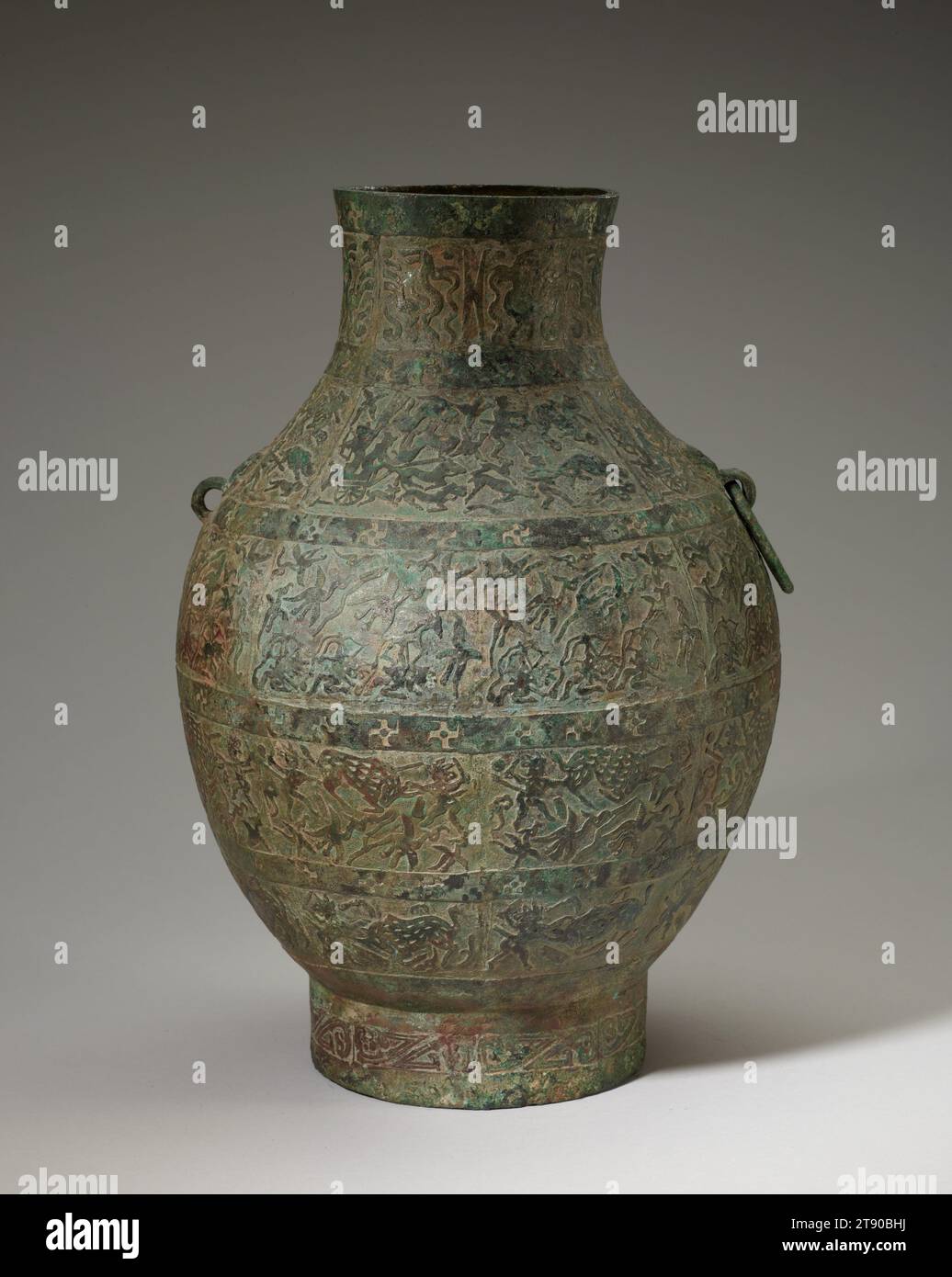 HU vaso del vino, V secolo a.C., 13 7/8 x 9 3/8 pollici, 6,4 libbre (35,24 x 23,81 cm, 2,9 kg), Bronzo, Cina, V secolo a.C., questa nave di stoccaggio fa parte di un importante gruppo di scene di caccia hu. Mostrano l’influenza dell’arte nomade della frontiera settentrionale della Cina. Le quattro bande principali raffigurano uomini che cacciano uccelli, cervi, cinghiali e tigri con lance, coltelli e archi. I pannelli sulle spalle della nave mostrano un arciere che spara dal retro di un carro a quattro cavalli con autista. Queste scene pittoriche dell'attività umana rappresentano una rivoluzionaria partenza nell'arte del bronzo. Foto Stock