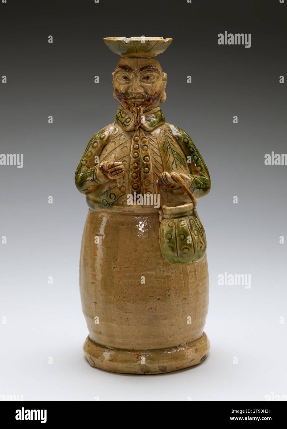 Candeliere in the Shape of a European Man, XVII secolo, sconosciuto giapponese, 12 x 5 x 4 7/8 pollici (30,48 x 12,7 x 12,38 cm), ceramica Oribe; gres smaltato, Giappone, XVII secolo, questo candelabro in gres prende la forma di un cosiddetto nanban, o "barbaro meridionale", una parola usata storicamente in Giappone per riferirsi agli europei. Qui, sopracciglia rosse e cespugliose e una barba, un naso prominente, occhi grandi e la sua camicia colletto mettono in risalto la sua estraneità. Lo smalto verde che ricopre il barattolo che porta, così come parte della sua camicia, è caratteristico della ceramica Oribe, realizzata nella regione del Mino Foto Stock