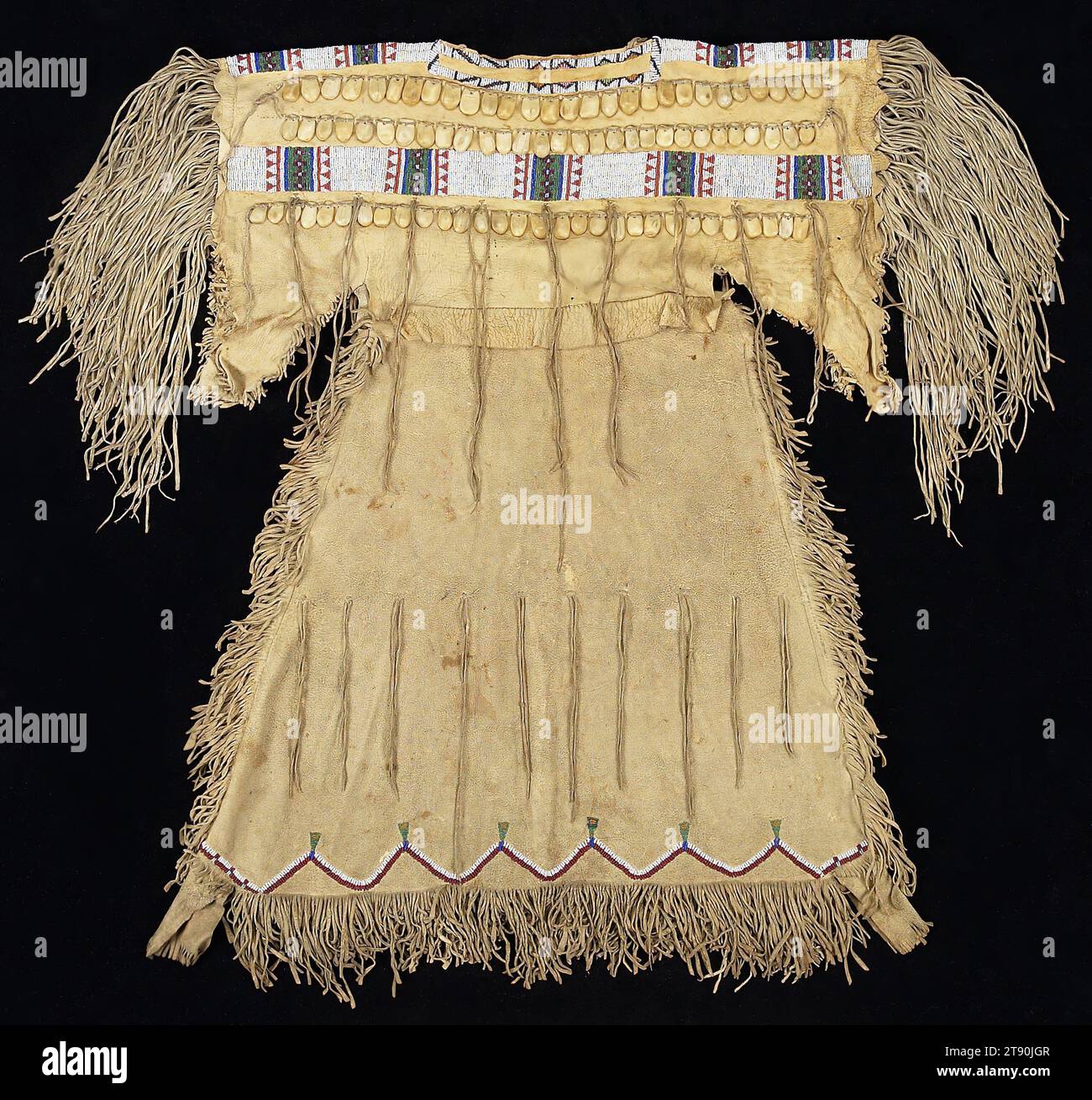 Vestito da bambina, c. 1860-1870, 35 3/4 x 26 poll. (90,8 x 66 cm) (compresa la frangia inferiore), pelle animale, perline, osso, Stati Uniti, nel XIX secolo, questo stile di abbigliamento fu introdotto nelle pianure nel XIX secolo, sostituendo un precedente disegno drappeggiato e legato comune tra i Tsistas (Cheyenne). I denti di alce, solo i due incisivi superiori, erano usati come decorazione, rappresentando una grande ricchezza a causa della loro scarsità. Quando l'alce diventa più difficile da ottenere, l'osso è stato scolpito per assomigliare ai denti e usato allo stesso modo, come su questo vestito. Il design del giogo con perline e dell'orlo è tipico dell'arte Tsistas Foto Stock
