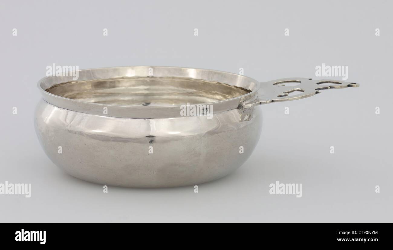 Porringer, 1725, Simeon Soumain, americano, 1685-1750, 2 1/8 x 8 1/4 x 5 3/4" (5,4 x 21 x 14,6 cm), Argento, Stati Uniti, XVIII secolo, questi due ritrattori dimostrano quanto poco questa forma sia cambiata in mezzo secolo a New York. Piatti poco profondi o tazze per l'uso quotidiano, i porringers generalmente contengono alimenti come zuppe o porridge. In genere, il corpo di un porringer viene sollevato e l'impugnatura viene fusa e saldata. Molte volte, gli stampi per elementi popolari come manici o beccucci erano condivisi tra i negozi di argentiere Foto Stock