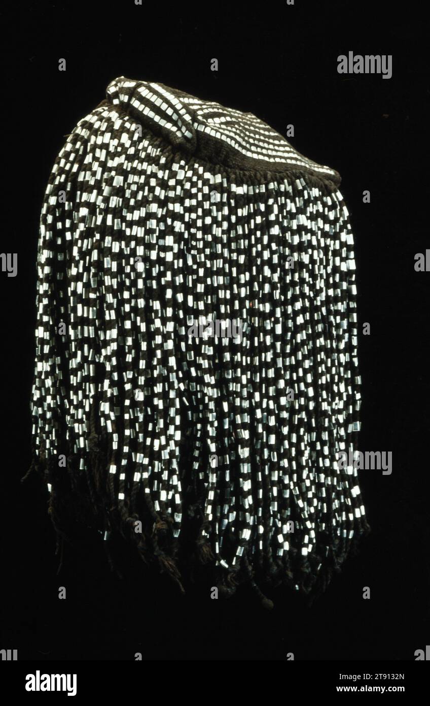 Copertura testa, 20° secolo, 12,25 x 6,5" (31,1 x 16,5 cm), cotone, nappine, nappine rivestite in metallo, Niger, nel XX secolo, il gorowije ine Hat è stato indossato dagli uomini Dogon in Mali per secoli. Questi cappelli sono realizzati in strisce di tessuto locale tinte con pigmenti marrone indaco o earhen, con lacci di cotone intrecciato sui lati e sul retro della corona. Questo cappello ha anche sottili strisce di alluminio come decorazione Foto Stock
