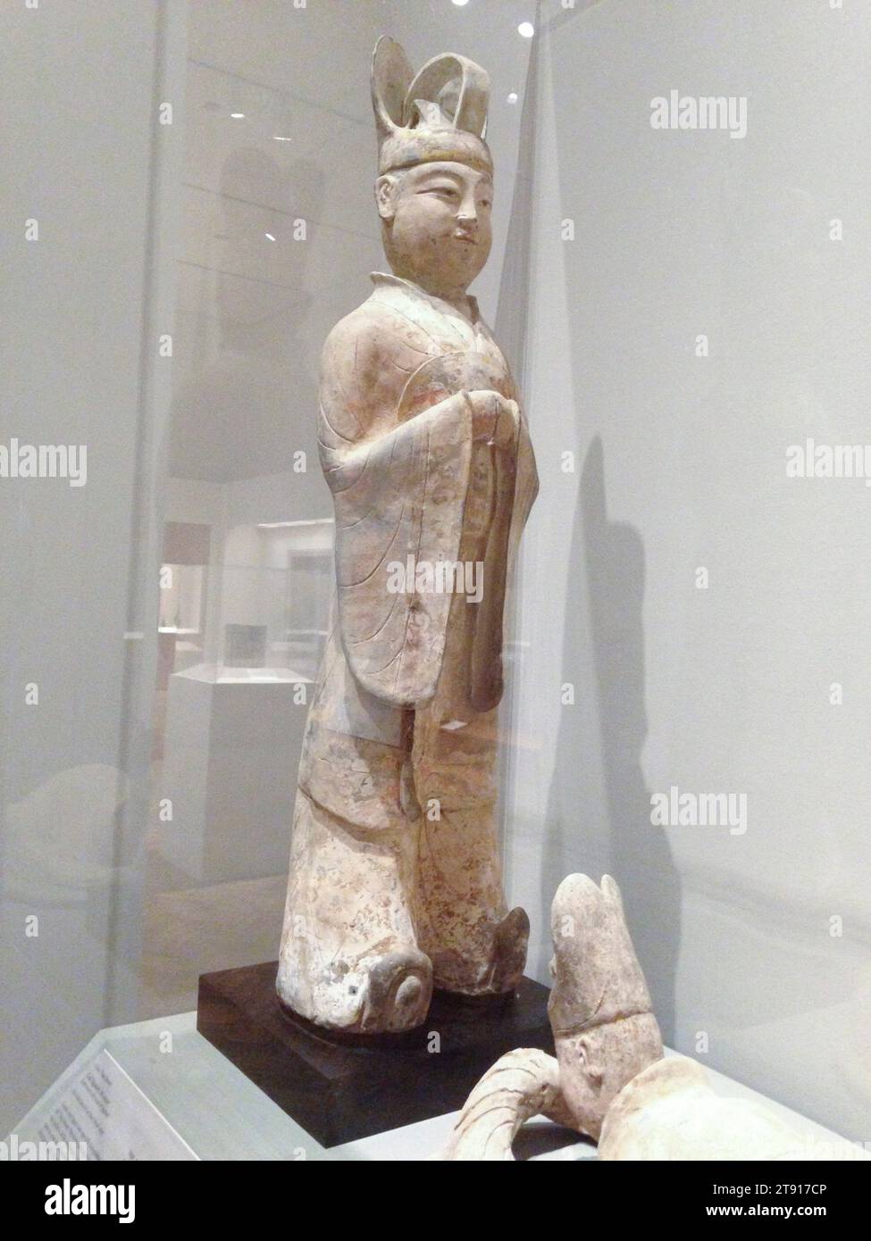 Dignitario civile, 618-906, 39 x 10 x 1/4 pollici (99,1 x 25,4 x 26 cm), terracotta con tracce di pigmenti, Cina, VII-X secolo, statue di tombe in ceramica si distinsero particolarmente durante la dinastia Tang. La pittura policroma di ottima qualità è stata applicata alla scultura in terracotta realistica elevando queste ceramiche a un nuovo livello di eccellenza. Il comportamento serio e dignitoso di un funzionario civile è catturato perfettamente in questa grande figura ben modellata. Elegante con il suo alto cappello da corte e il suo abito lungo con maniche fluide, questo dignitario ha un volto realistico e gli stringe le mani con rispetto Foto Stock