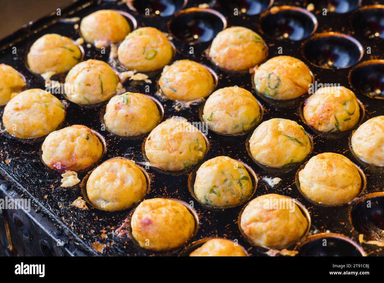 I takoyaki tradizionali in una padella stampata, i takoyaki sono spuntini giapponesi a forma di palla, visti a Osaka, in Giappone Foto Stock