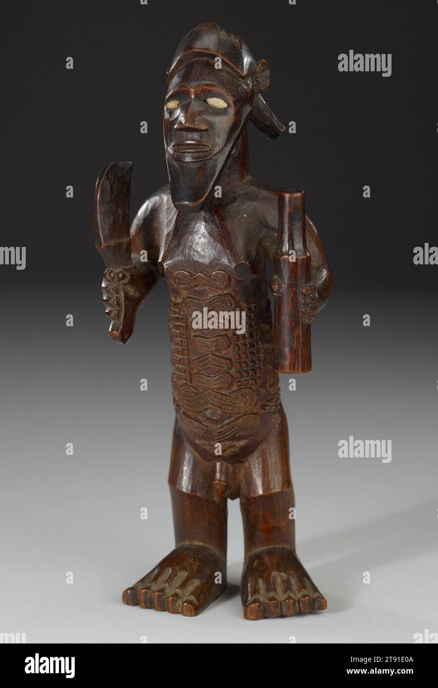 Figura antenata, inizio XX secolo, 7 5/8 x 2 7/8 x 2 1/8 pollici (19,37 x 7,3 x 5,4 cm), legno, porcellana, Repubblica Democratica del Congo, XX secolo, coltello e bottiglia (importati dall'Europa) sono indicazioni di autorità, suggerendo che questa figura ancestrale rappresenti un uomo di alto rango, molto probabilmente un capo. I grandi piedi, notate i dettagli delle dita, simboleggiano la stabilità, mentre i piccoli frammenti di porcellana bianca utilizzati per gli occhi esaltano il potere visionario della figura. Il suo vero potere, tuttavia, era nascosto Foto Stock