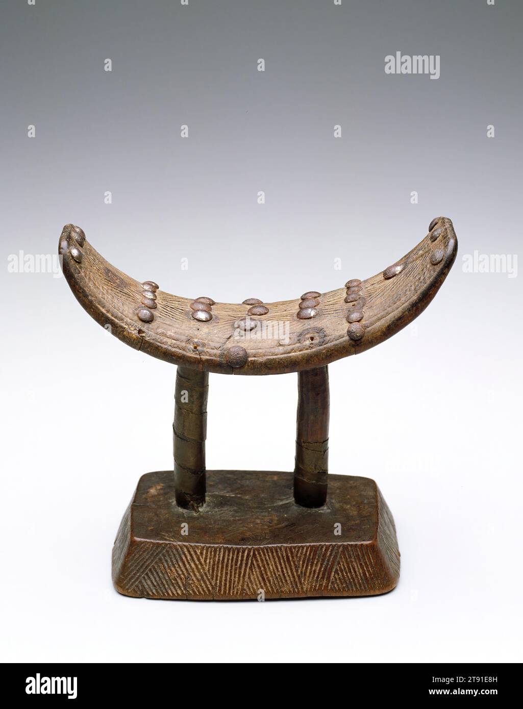 Poggiatesta, XIX secolo, (15,7 x 15,7 x 8,9 cm), legno, rame, Repubblica Democratica del Congo, XIX secolo, i Luba usano poggiatesta per proteggere l'elaborata coiffure che è importante per la loro cultura. La coiffure, una tradizione vista in molte culture africane, rappresenta l'età, lo status e il genere ed è tipicamente adornata con metallo, perline e fascino per il potere spirituale. Oltre alla coiffure, la scarificazione è anche un elemento importante nella tradizione Luba perché rappresenta lo status e viene spesso fatto per commemorare un rito di passaggio. Foto Stock