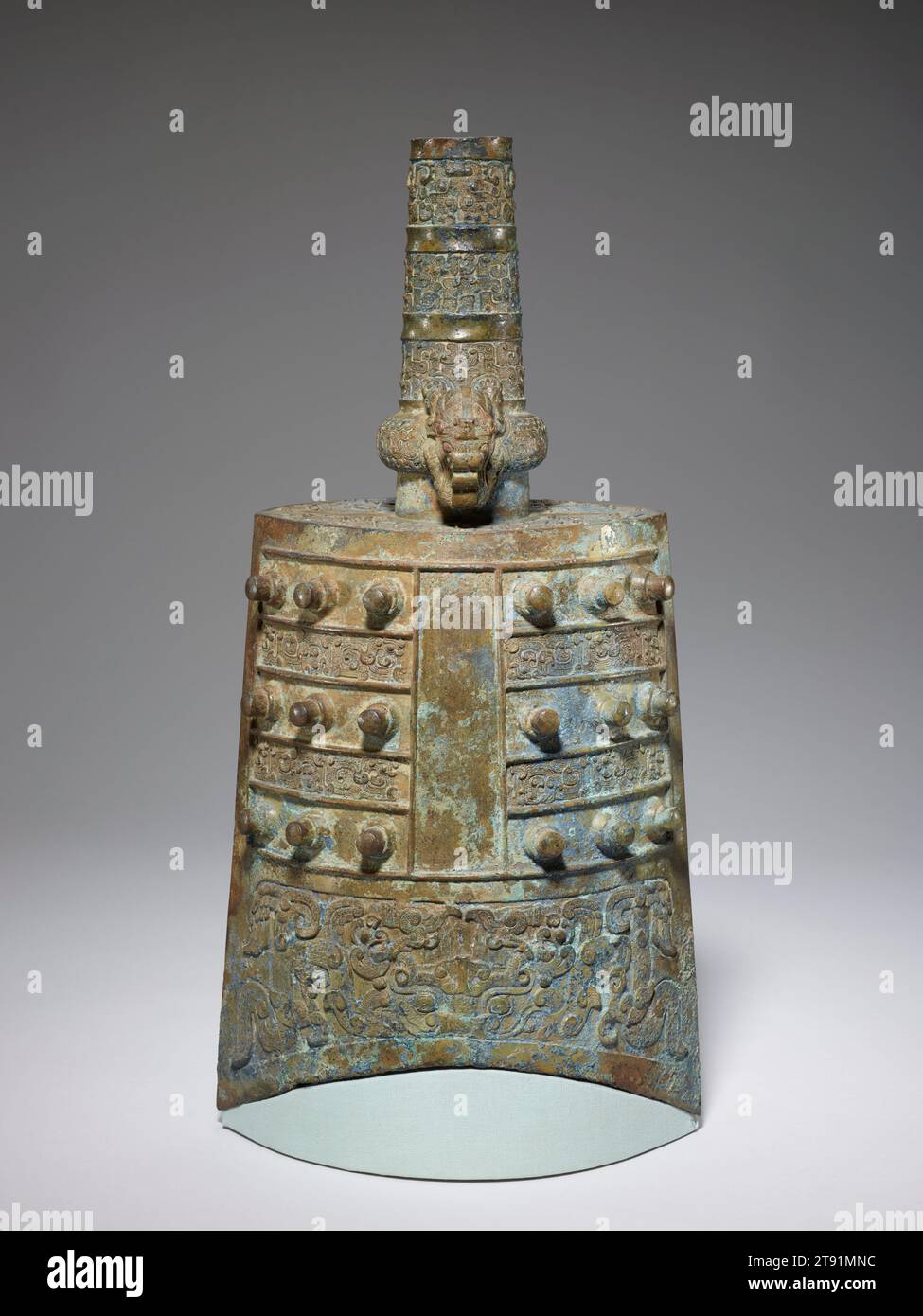 Campana di Yong, fine vi-V secolo a.C., 23 pollici (58,42 cm), Bronzo, Cina, vi-V secolo a.C., quando fu fatta questa campana, intorno al 500 a.C., le campane cinesi si erano già evolute nel corso di 800 anni. Erano strumenti musicali sofisticati. Questa campana è chiamata yong, la quintessenza del tipo di campana trovata nelle tombe di alto rango del tardo Zhou. A differenza del tipo bo, visto altrove in questa mostra, ha un fondo a forma di arco, lati dritti, boss cilindrici e uno stelo colonnare (yong) con un dispositivo di sospensione ad anello che fa inclinare la campana verso il giocatore piuttosto che rimanere dritta verso l'alto e verso il basso. Foto Stock