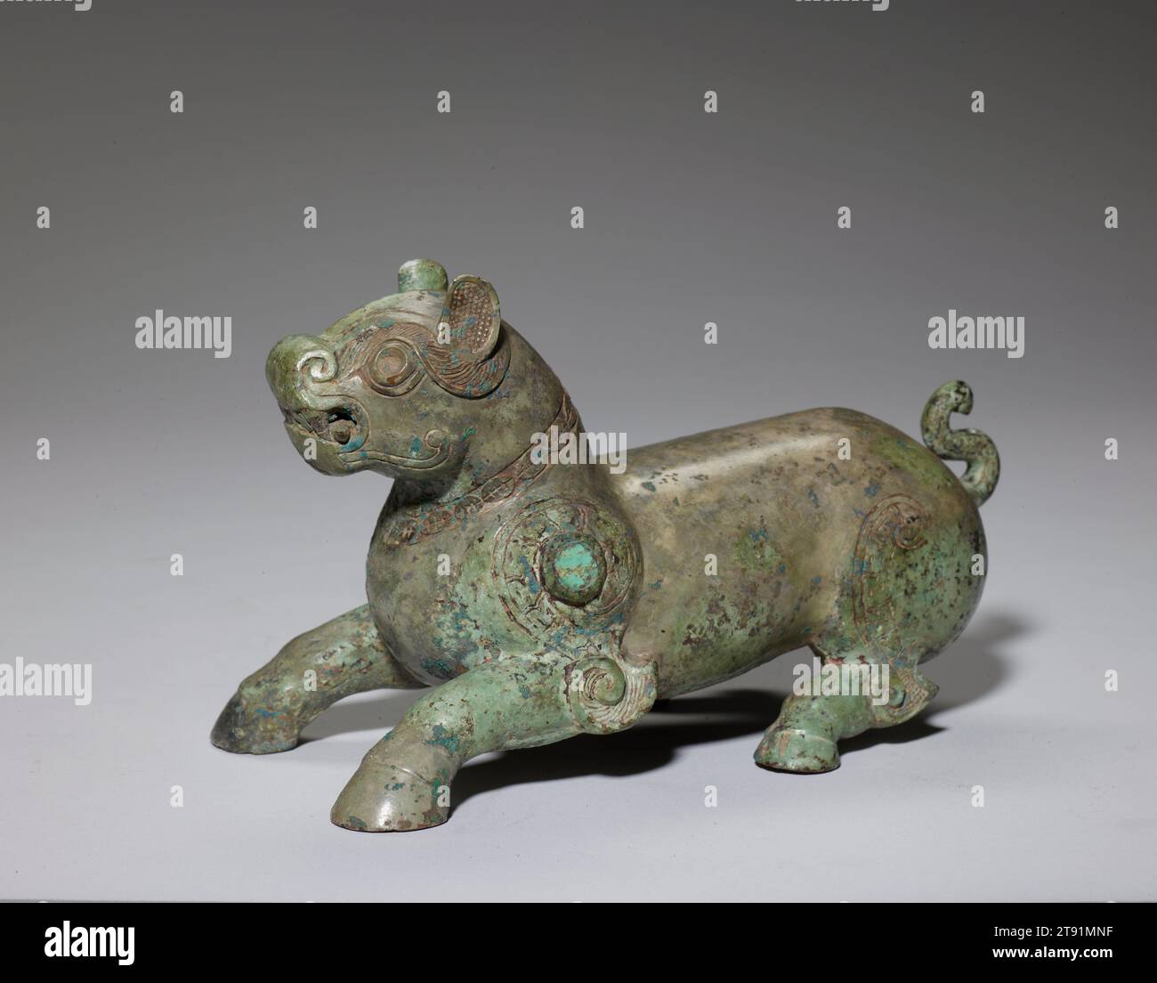 Bestia mitologica, V secolo a.C., 4 7/8 x 8 3/8 x 4 3/16 pollici, 2,9 libbre (12,4 x 21,2 x 10,7 cm, 1,3 kg), bronzo e turchese, Cina, V secolo a.C., questa fantastica creatura combina caratteristiche di vari animali, tra cui una testa simile a una tigre e zoccoli di bufalo d'acqua. La scultura cattura il momento prima che la creatura stia per saltare, e l'effetto scultoreo si ottiene attraverso le lunghe e ampie curve del corpo. La potenza delle spalle è enfatizzata da un motivo a spirale e da un anello rialzato con intarsi turchese. Gli occhi sono anche intarsiati di turchese. Foto Stock