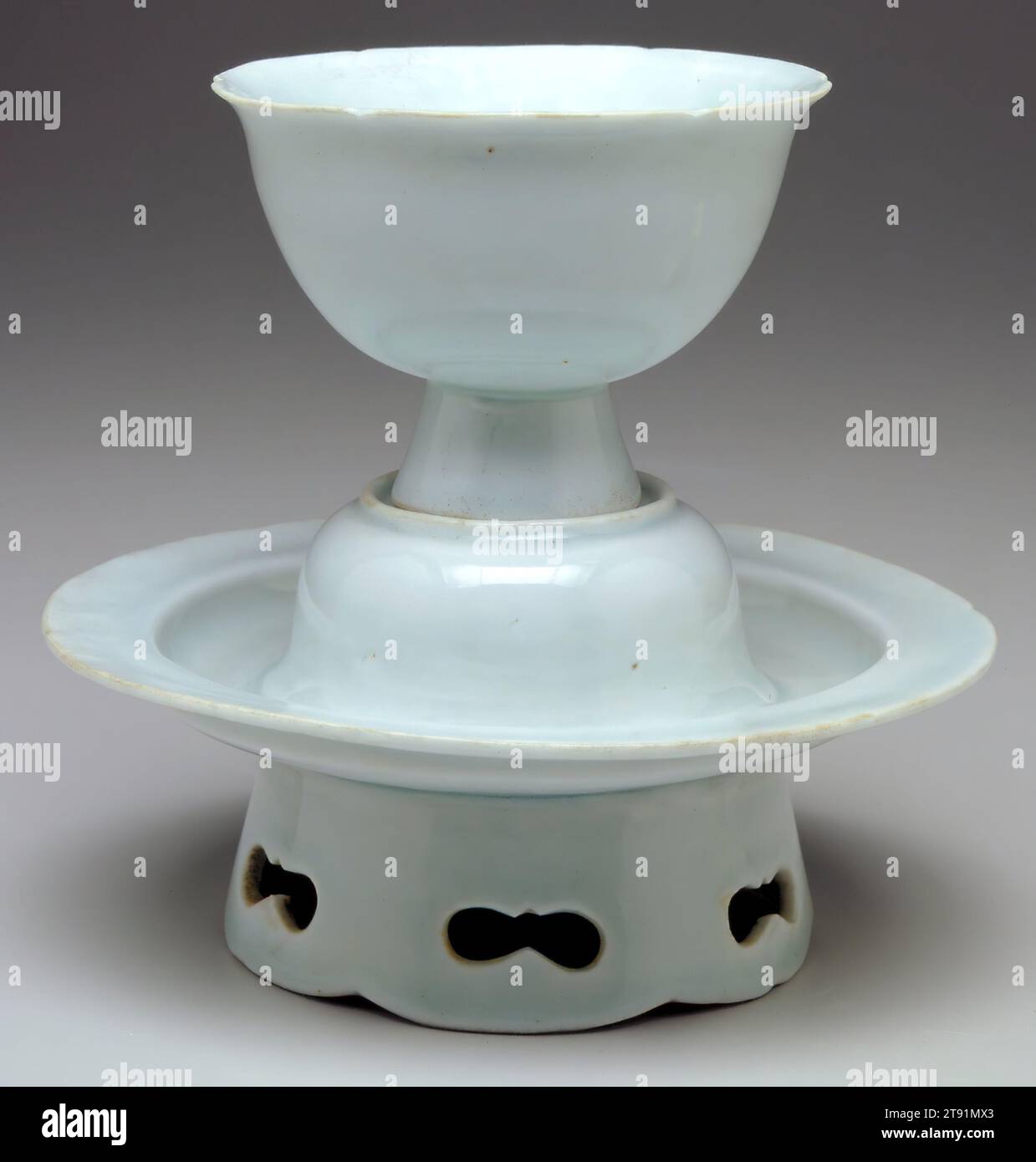 Wine Cup and Stand, 11th Century, 5 1/2 x 6" (13,97 x 15,24 cm), porcellana di ceramica Qingbai con smalto blu pallido, Cina, XI secolo, stand di coppa Qingbai con motivi trafilati apparvero per la prima volta nell'XI secolo. Questo tipo di coppa di porcellana e stand in vaso sottile può essere visto nei dipinti della dinastia Song (960-1279) che illustrano scene di banchetti. Destinati a cene eleganti, questi vasi devono essere visti nel contesto di altre stoviglie Qingbai come le ciotole, i piattini e i piattini qui illustrati Foto Stock