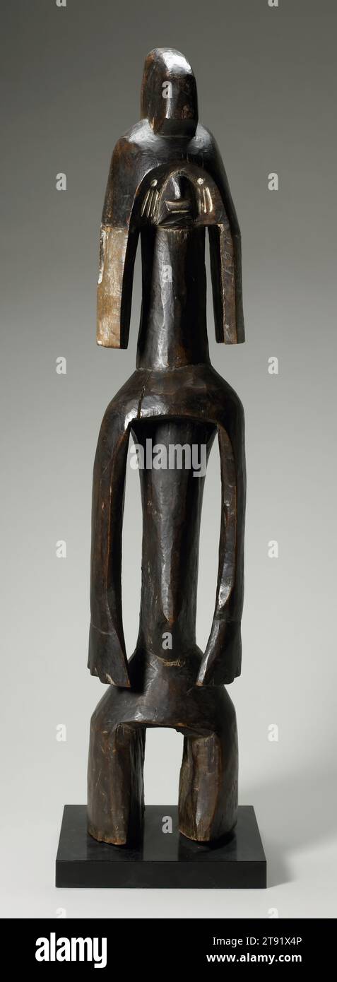 Figura, XIX-XX secolo, 36 1/2 x 7 pollici (92,71 x 17,78 x 17,78 cm) (senza base), legno, pigmento, Nigeria, XIX-XX secolo, i Mumuye della Nigeria nordorientale sono noti per le loro impressionanti figure, spesso asimmetriche. Le caratteristiche di definizione includono corpi allungati, bracci ad ala e teste piccole con facce stilizzate. Mentre la maggior parte di loro sono senza sesso, le figure femminili possono essere riconosciute dalla presenza di buchi nei lobi delle orecchie - come è il caso qui. Tali sculture rituali potevano essere utilizzate da divinatori, guaritori, giudici e creatori di pioggia. Alcuni servivano come simboli di stato per anziani importanti Foto Stock