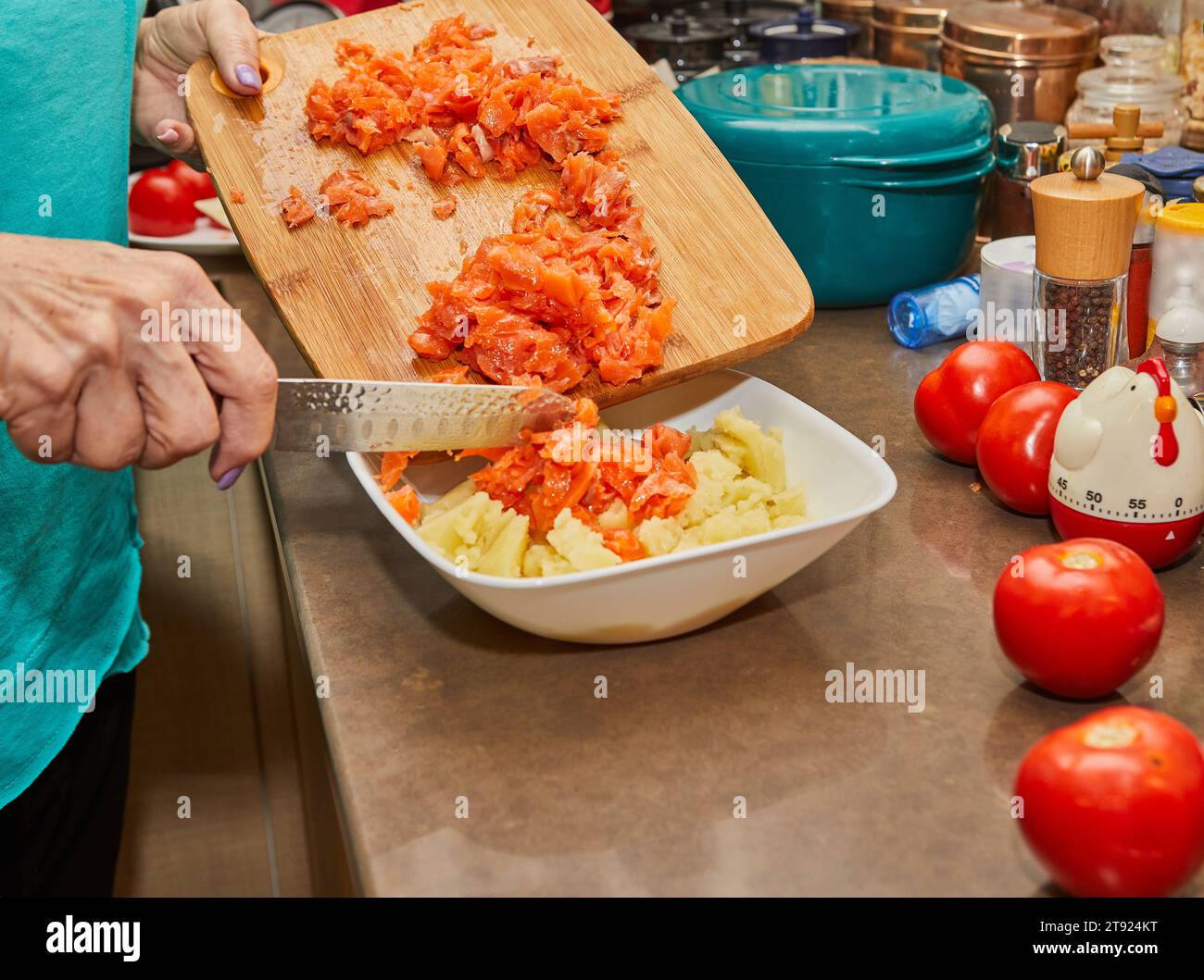 Lo chef mette i pomodori tagliati finemente in purè di patate. Foto Stock