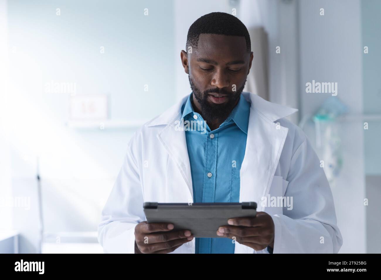 Medico maschio afroamericano che utilizza la compressa nella stanza d'ospedale Foto Stock