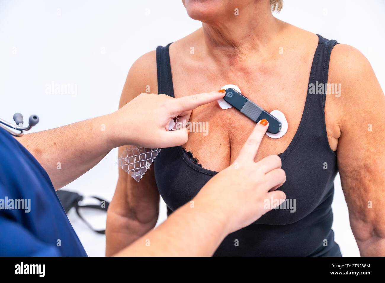 Medico donna che mette donna con problemi cardiaci sottoposti a test ECG Holter monitor con dispositivo innovativo sul torace Foto Stock