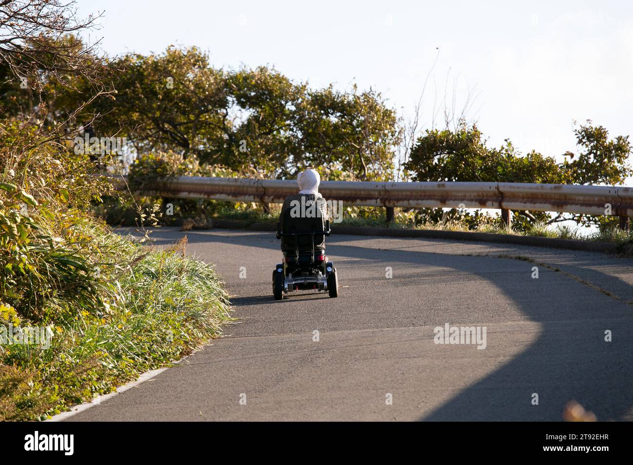 Una donna anziana che guida un veicolo elettrico per la mobilità in Giappone. Foto Stock