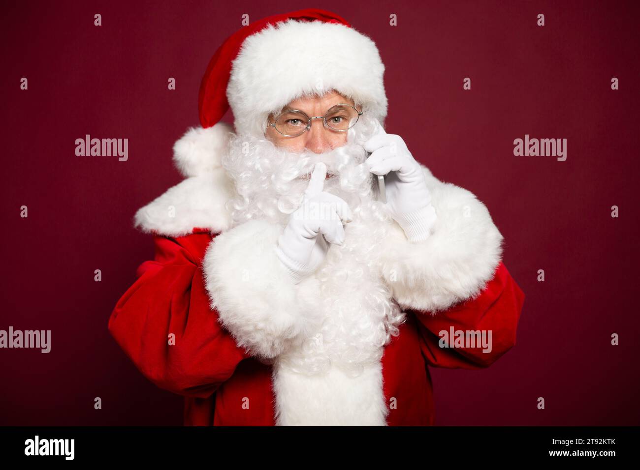 La foto di Babbo Natale sorridente sta posando su uno sfondo rosso nell'atmosfera natalizia Foto Stock