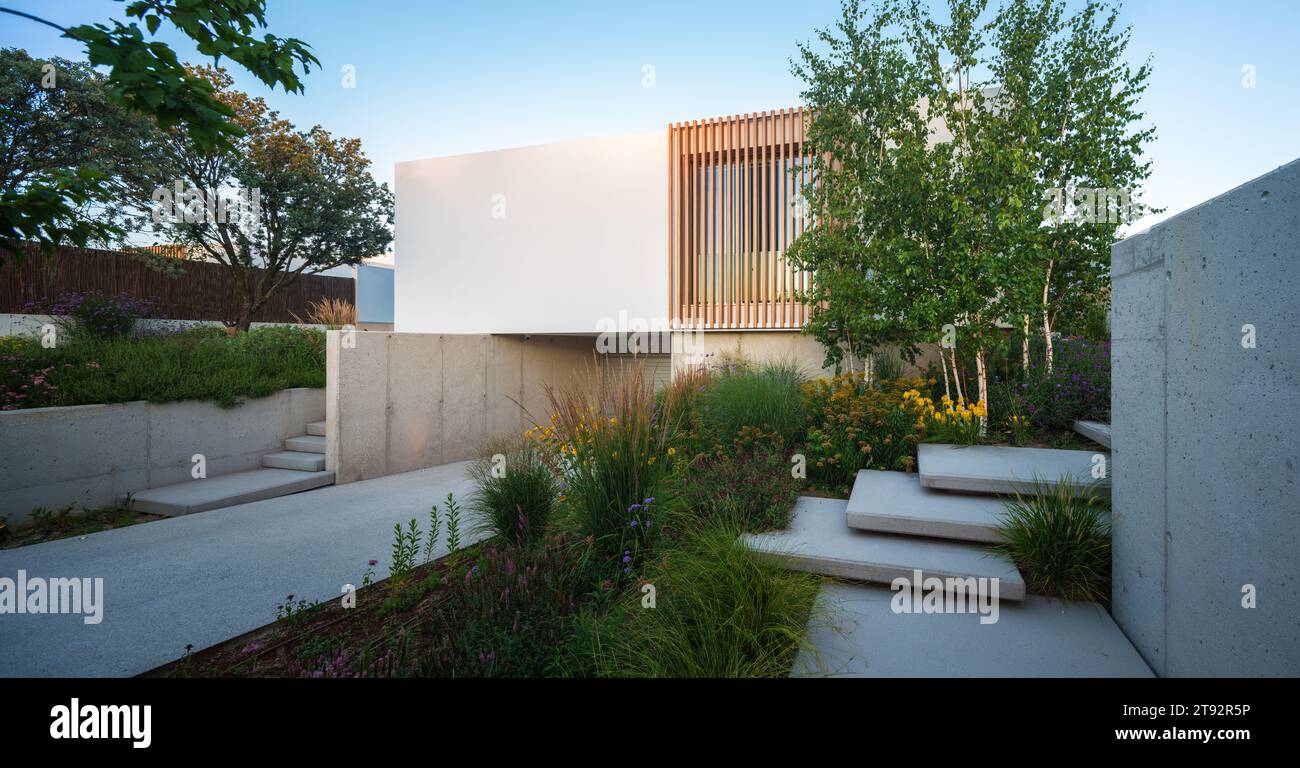Una casa di lusso con una piscina minimalista e bianca e giardini potrebbe avere un design contemporaneo ed elegante Foto Stock