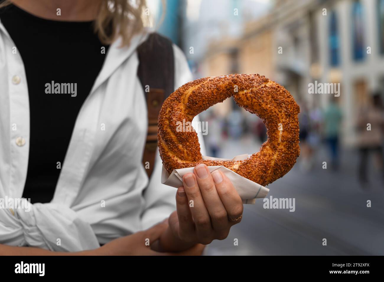 La donna tiene un primo piano di un tradizionale bagel turco Simit per strada. Fast food turco. Foto Stock
