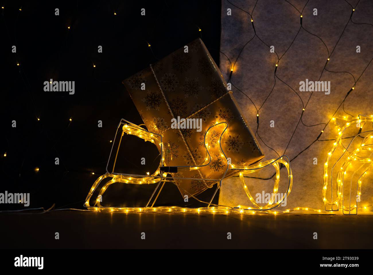 Tuffati nello spirito natalizio con un primo piano di un regalo di Natale avvolto in carta dorata adornata da scintillanti fiocchi di neve. L'angolo inferiore del gif Foto Stock