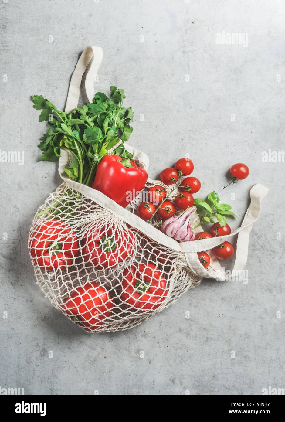 Vista dall'alto di varie verdure ed erbe nella sacca riutilizzabile in plastica gratuita presso il tavolo da cucina grigio in cemento Foto Stock