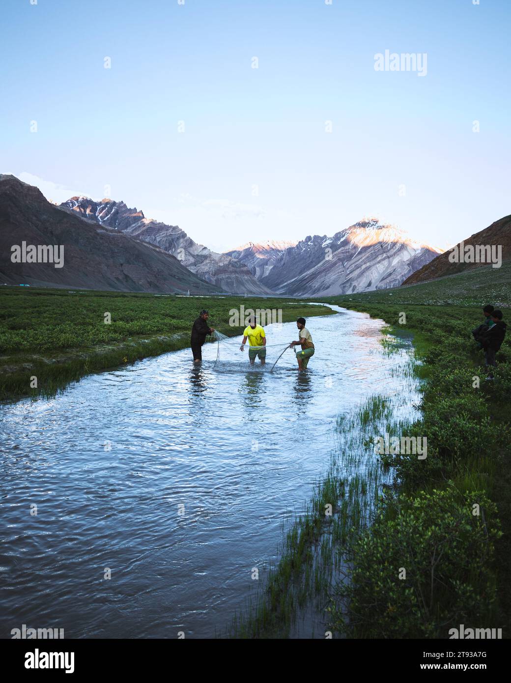 Pochi adolescenti che cercano di pescare in un ruscello in mezzo al prato Foto Stock