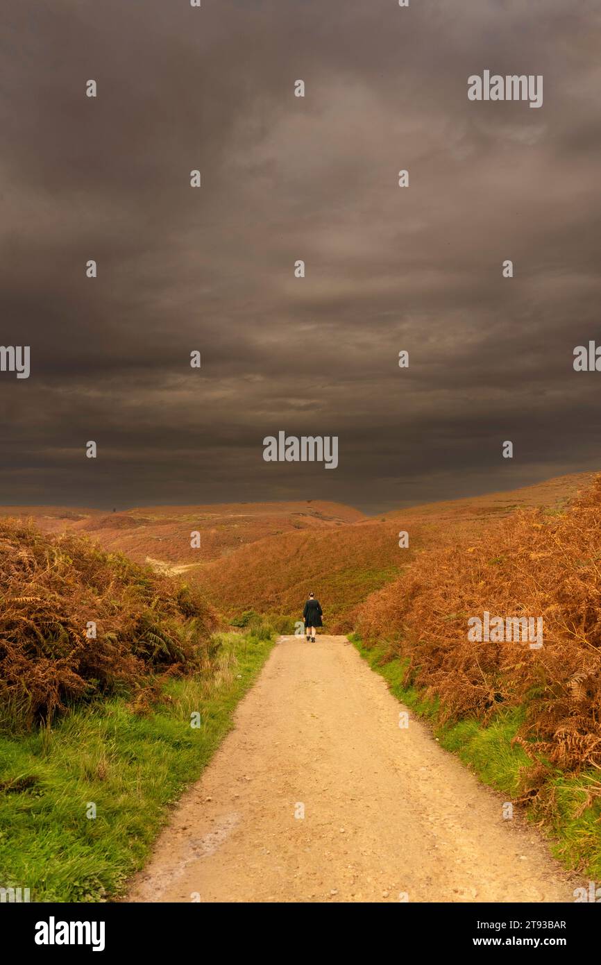 Ragazza vestita che si allontana dalla macchina fotografica lungo una pista umida e fangosa a Osmotherly, North Yorkshire, Inghilterra, Regno Unito Foto Stock