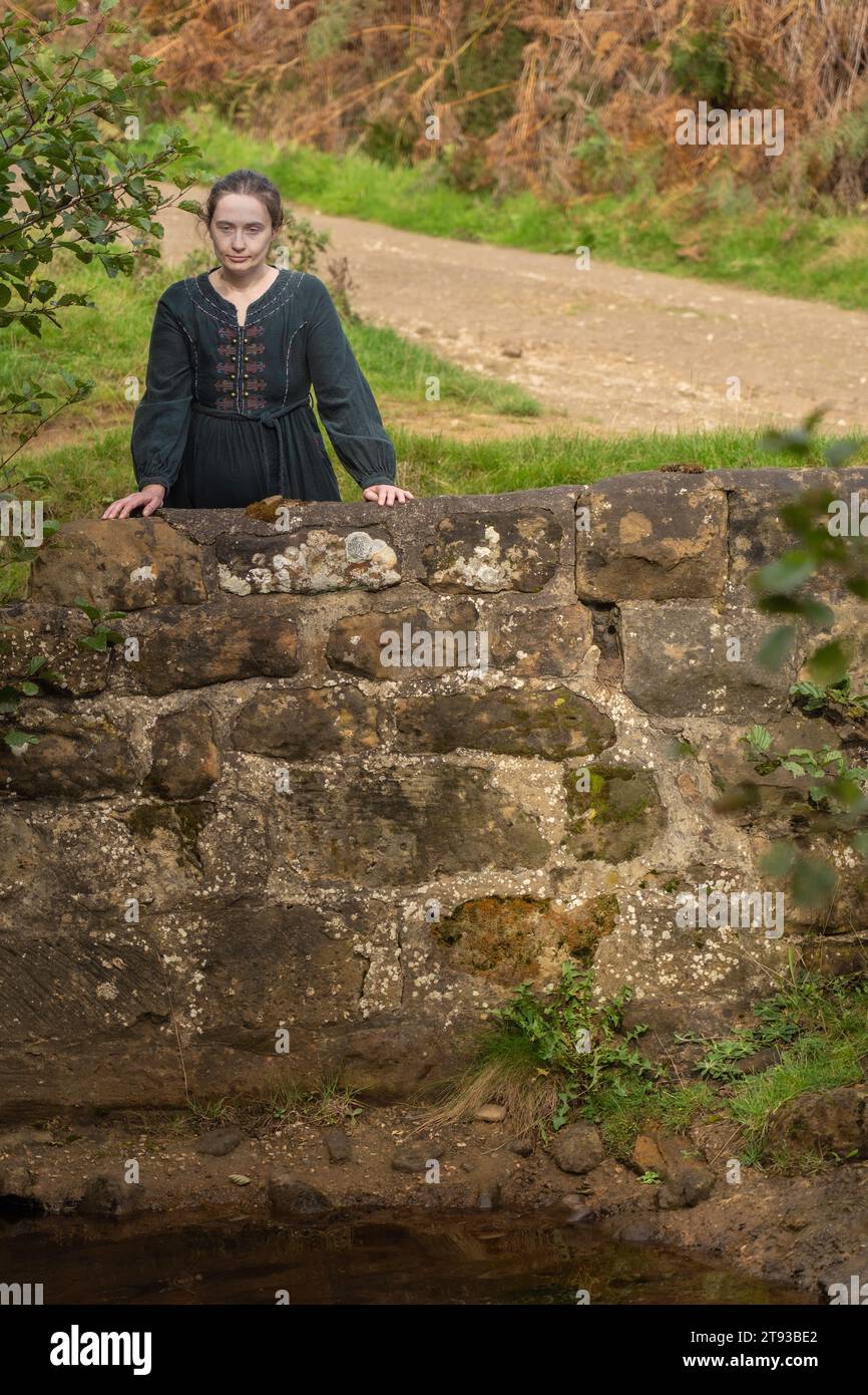 La ragazza era appoggiata contro il muro da un ruscello che contemplava la vita nella campagna di Osmotherly, North Yorkshire, Inghilterra, Regno Unito Foto Stock
