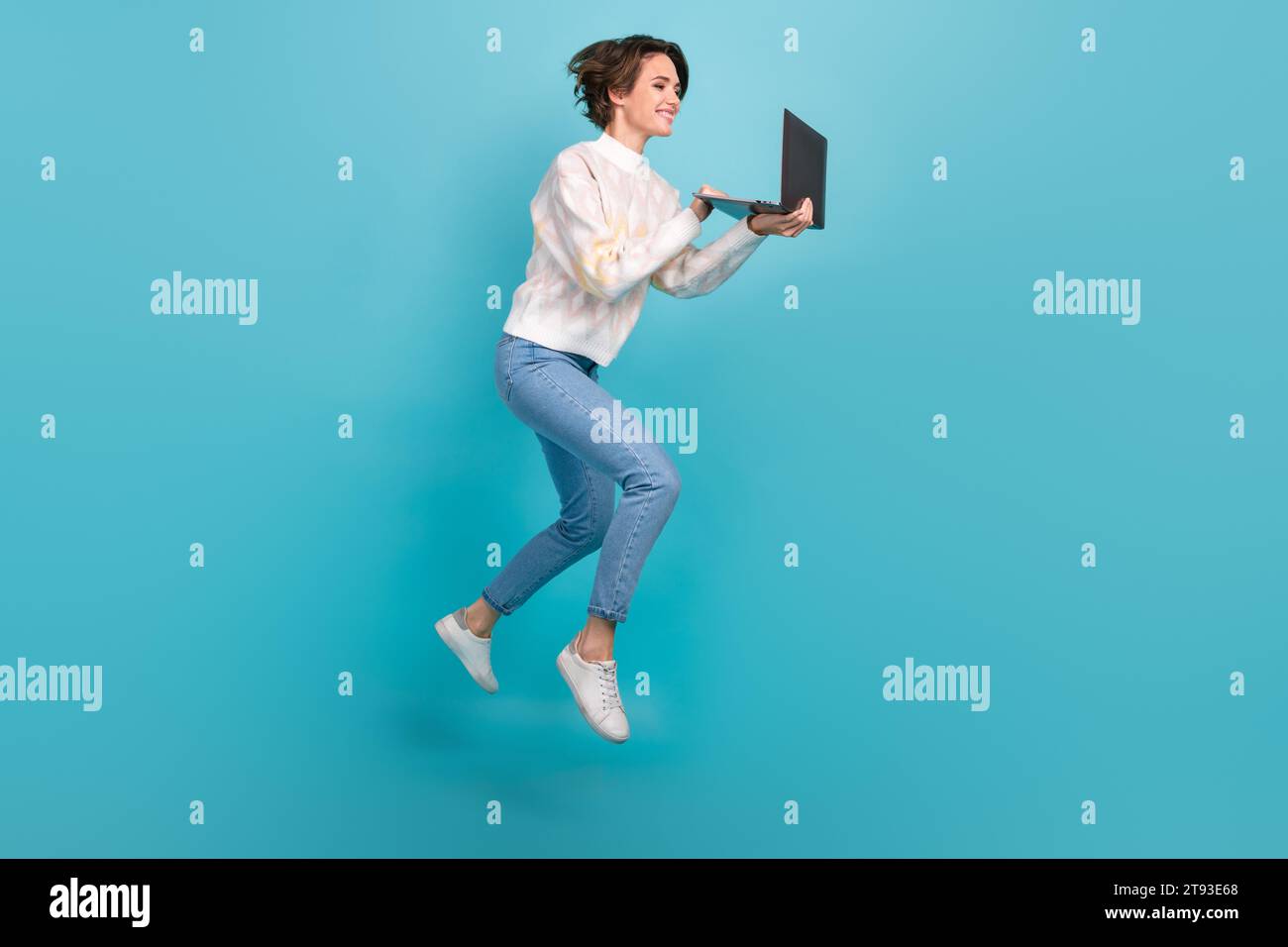 Foto a tutta lunghezza del corpo del project manager Jump Running, giovane donna indossa jeans pullover denim, lavoratrice remota, isolata su sfondo blu Foto Stock