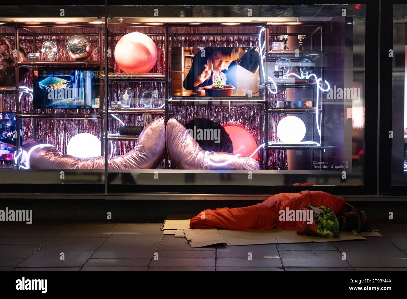 Senzatetto che dorme sul marciapiede all'esterno del grande magazzino John Lewis finestra festiva lungo Oxford Street, Londra, Inghilterra Foto Stock