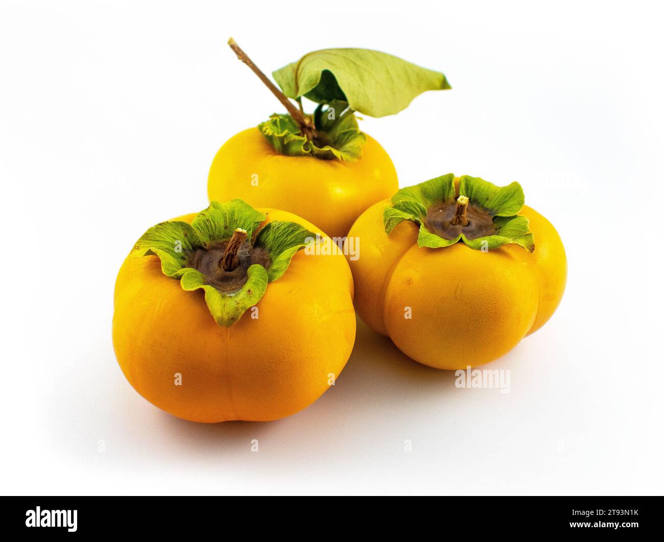 Foto di un cachi asiatico fuyu maturo con foglie e gambo intatti Foto Stock