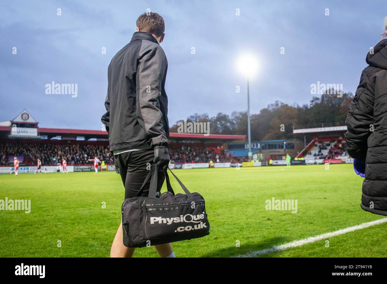 Fisioterapista professionista della squadra sportiva in attesa del permesso di entrare nel campo di gioco per trattare il calciatore ferito Foto Stock