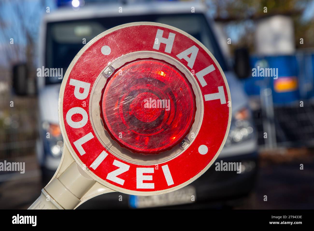 Controllo della polizia: Primo piano di una cazzuola della polizia con l'iscrizione tedesca HALT POLIZEI (Stop Police) davanti a un'auto della polizia Foto Stock Controllo della polizia: Primo piano di una cazzuola della polizia con l'iscrizione tedesca HALT POLIZEI (Stop Police) davanti a un'auto della polizia Foto Stock