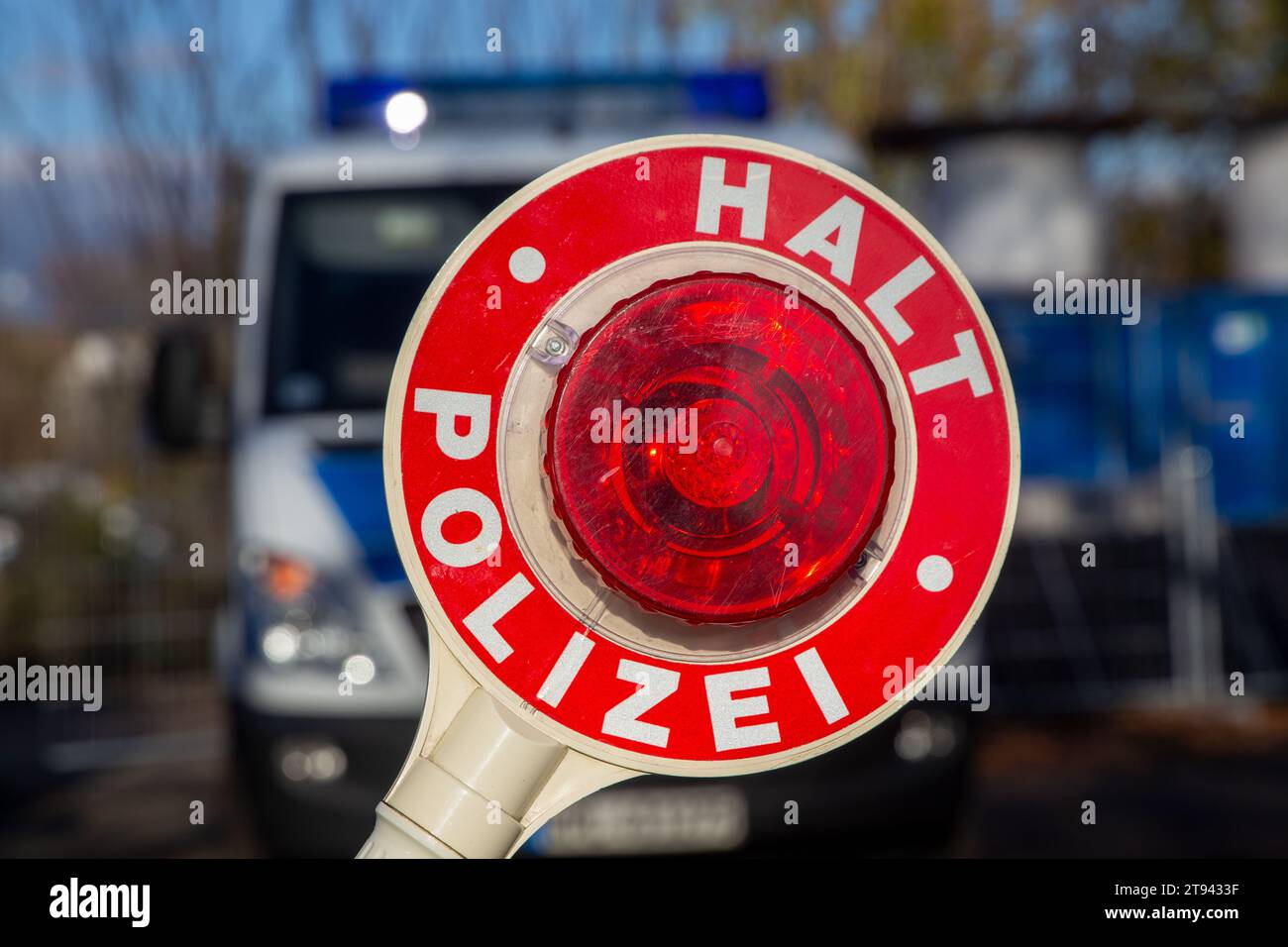 Controllo della polizia: Primo piano di una cazzuola della polizia con l'iscrizione tedesca HALT POLIZEI (Stop Police) davanti a un'auto della polizia Foto Stock Controllo della polizia: Primo piano di una cazzuola della polizia con l'iscrizione tedesca HALT POLIZEI (Stop Police) davanti a un'auto della polizia Foto Stock