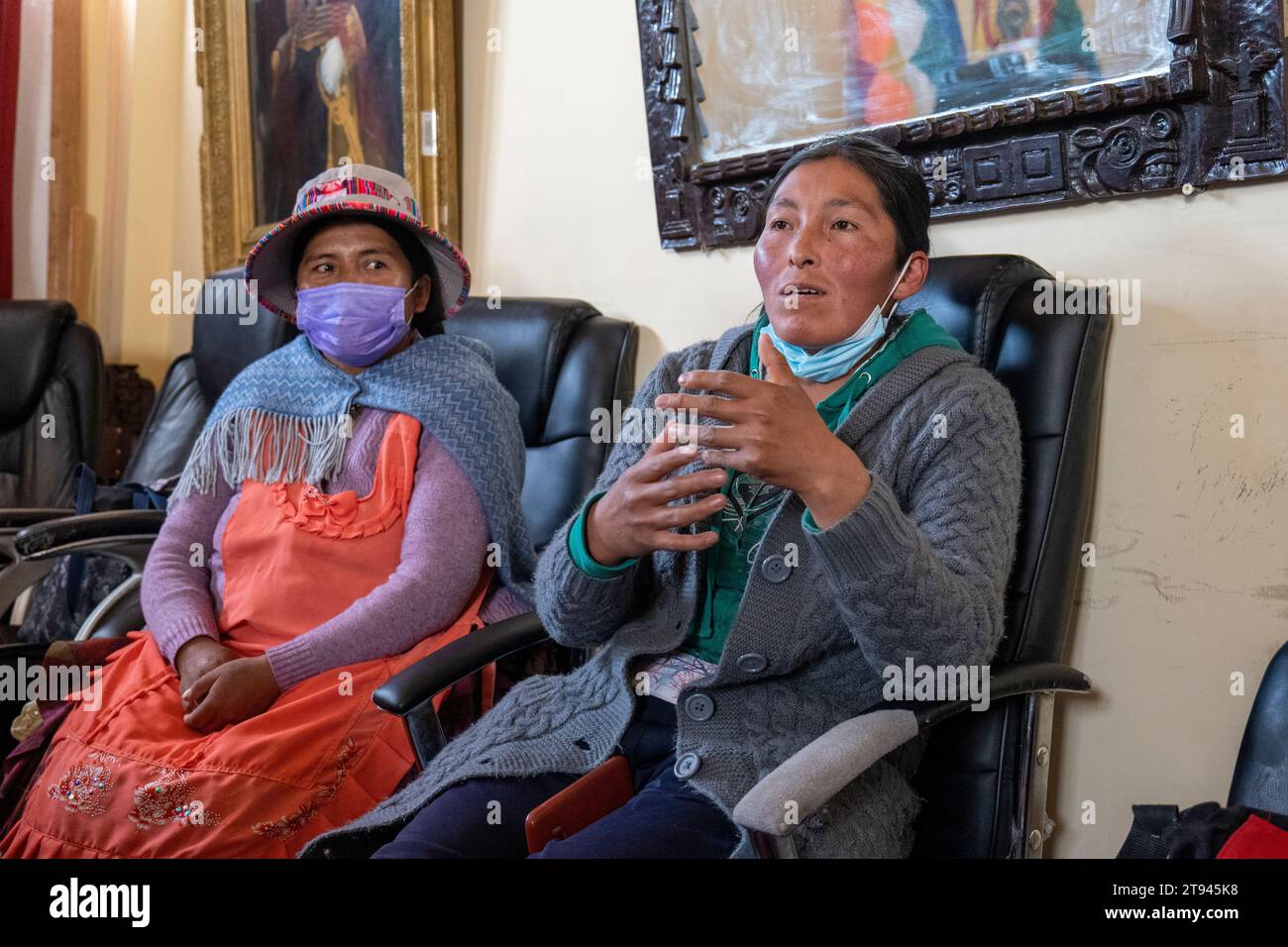 Viacha, la Paz, Bolivia – 16 agosto 2022: Due donne boliviane con maschere parlano al pubblico in una sala riunioni Foto Stock