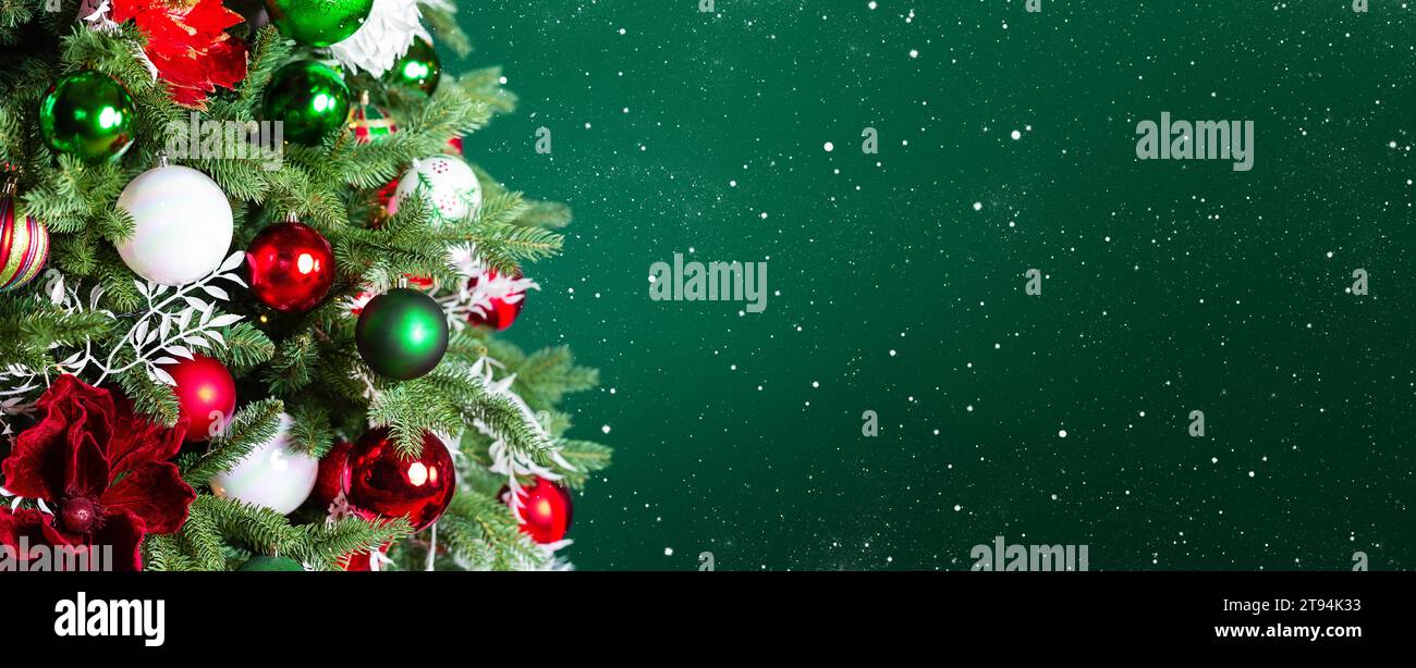 Albero di Natale con ornamenti, palle e luci su sfondo verde scuro. Buon Natale e un biglietto d'auguri per l'anno nuovo. Vacanze invernali backgroun Foto Stock