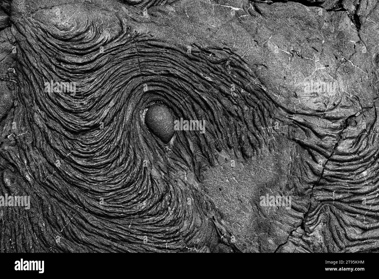 Background: La risorsa grafica della natura. Una scena monocromatica di lava vulcanica nera che scorreva intorno a una roccia sull'isola di Santiago, uno dei Galápag Foto Stock