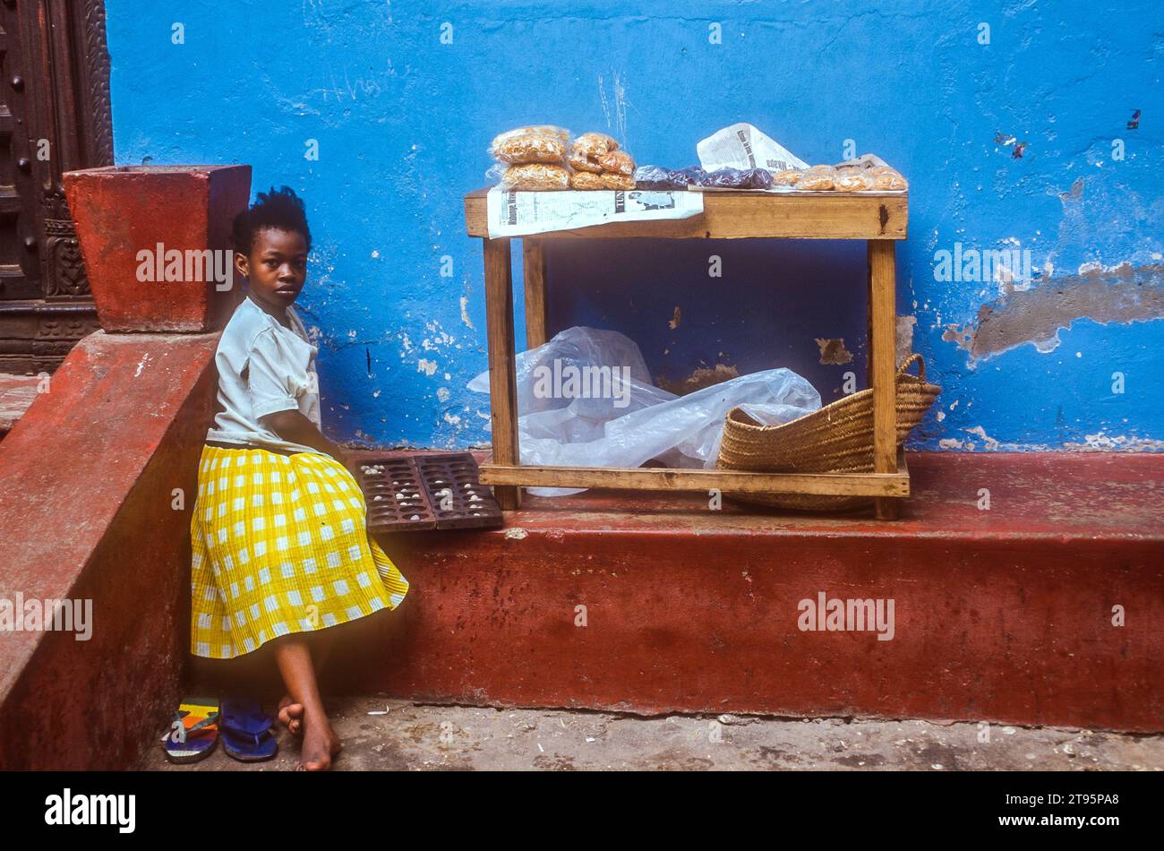 Giovane ragazza che aspetta fuori da un panificio a Zanzibar, in Africa orientale Foto Stock
